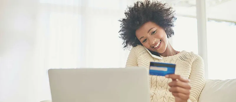 Mulher segurando um cartão de crédito e um computador