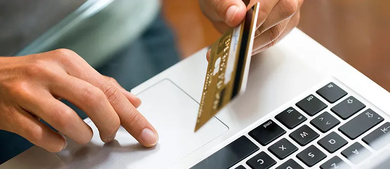 Pessoa mexendo no computador com o cartão de crédito