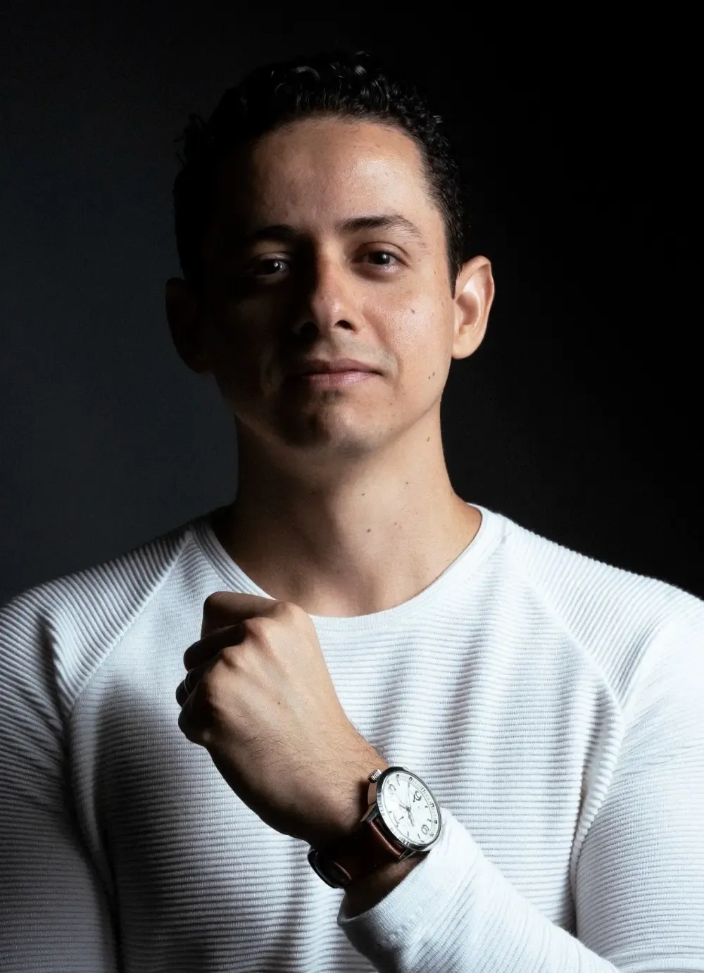 Mentor jovem de camiseta branca olhando pra câmera